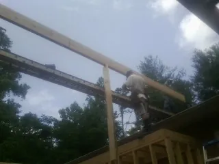 Carpenter setting a ridge beam over a new addition frame — Ice Dam Removal by Roofing Brothers in Candor