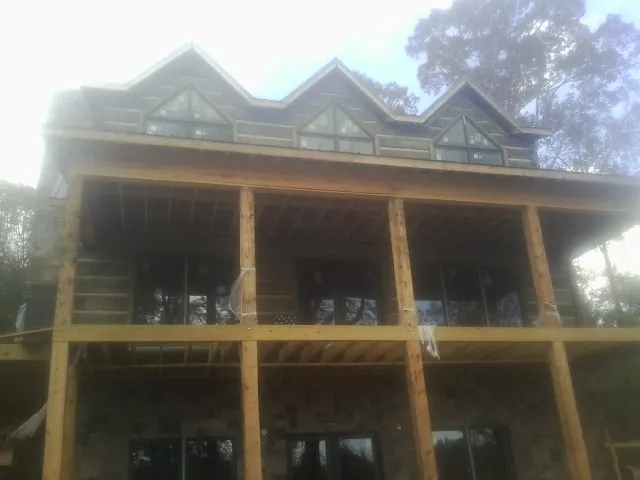 Dormers and porch framing on a large log home under construction — Roof Coating work by our crew in Candor