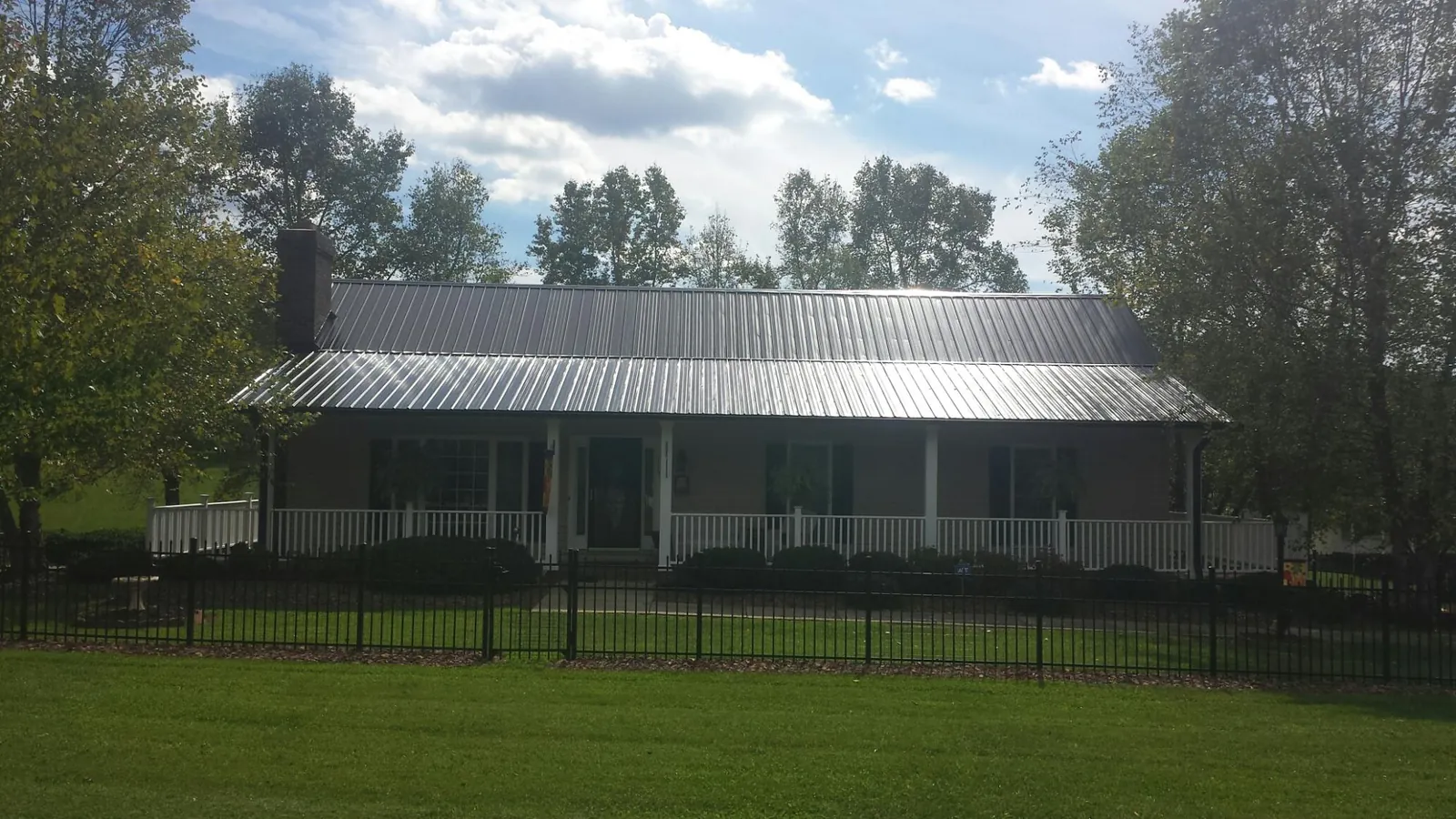 Gray metal roof on a brick ranch with a full width front porch — Gutter Guard Installation work by our crew in Candor